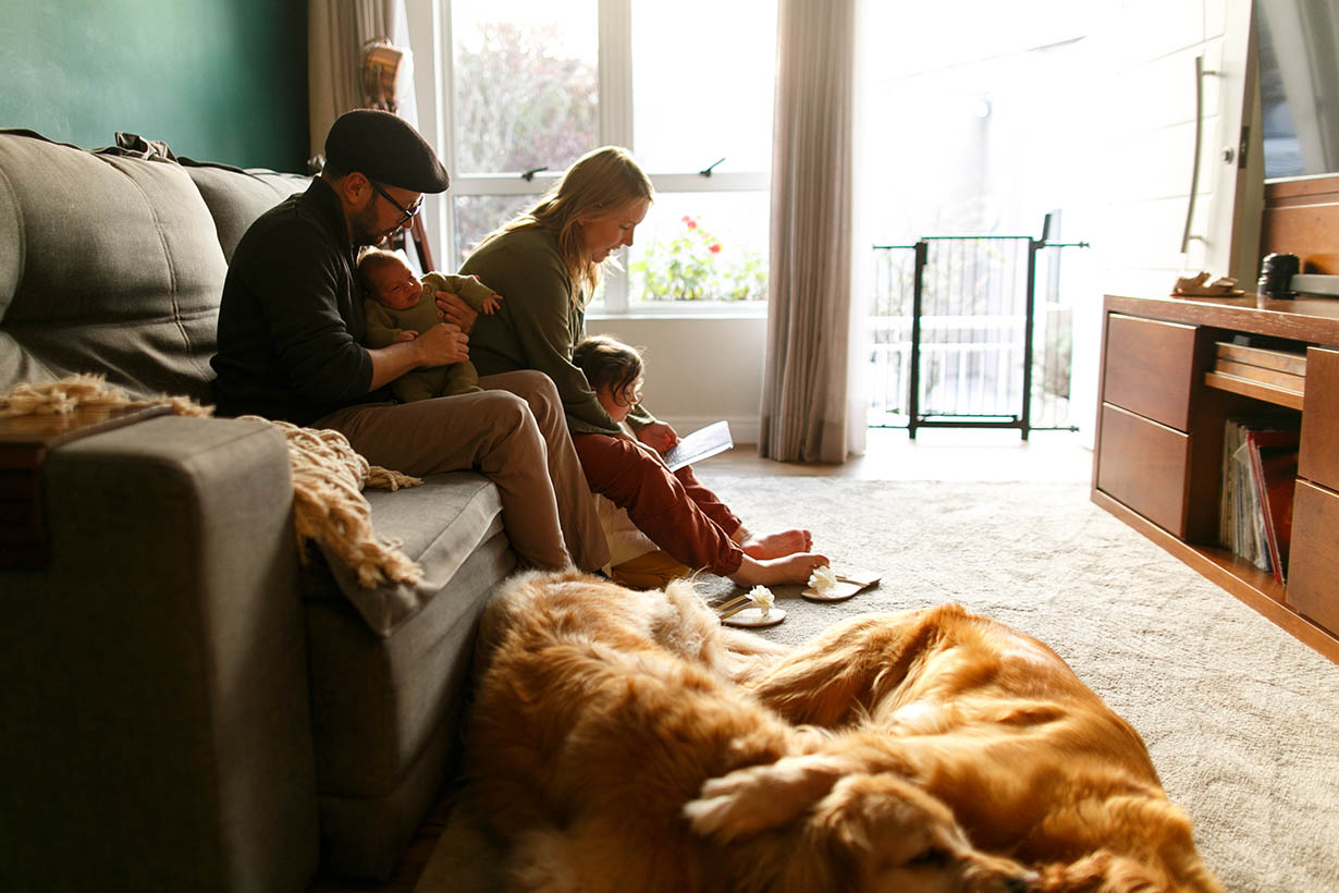 Young Happy Family with newborn baby sitting on the sofa in the living room Young happy family with newborn baby sitting on the sofa