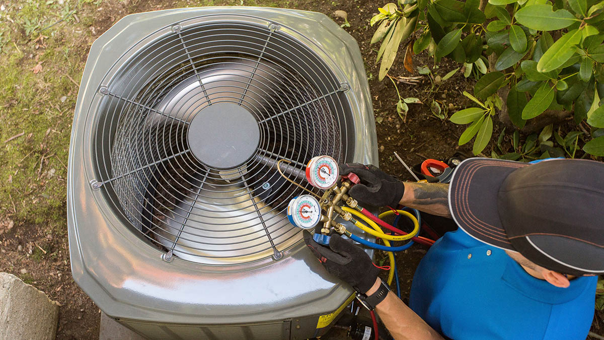 Is it Bad for My Central Air Conditioning to Run Constantly? 10 Photo from above of technician performing a maintenance test on an air conditioning unit